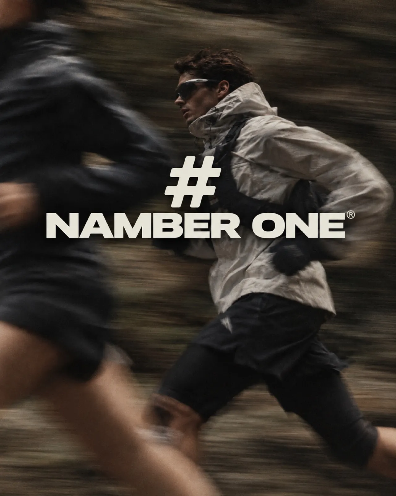 AI-generated campaign visual: two runners in motion blur on a mountain trail, one in a pale technical jacket and sunglasses, with a large # sign and the brand name set over them.