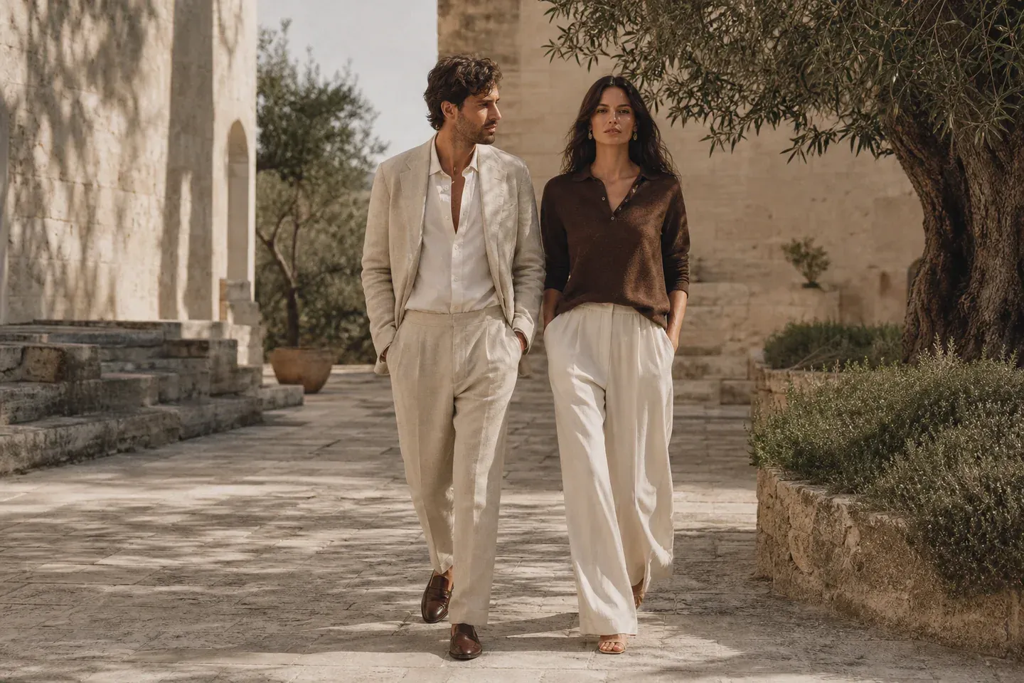 AI-generated image: a man in a light beige suit and a woman in a brown polo and cream trousers walk through a sunlit stone courtyard.